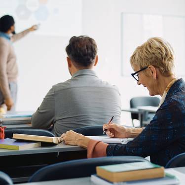 Smiling mature woman takes notes during education training class.