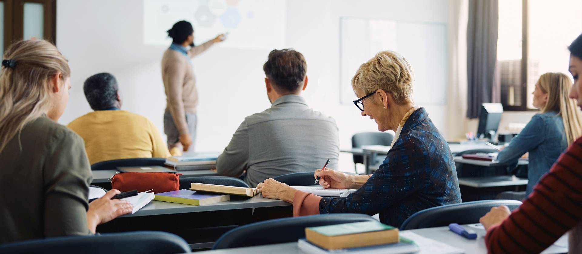 Smiling mature woman takes notes during education training class.