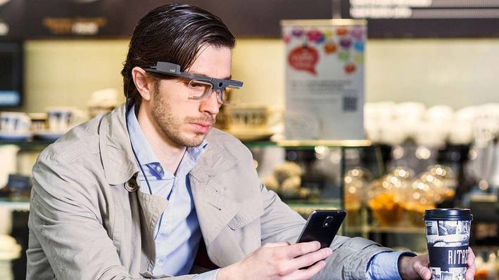 Ein Mann, der eine Tobii Pro Glasses 2 Brille trägt, bedient ein Smartphone.