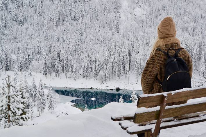 Myrthe Schäpkens auf einer Bank in Winterlandschaft