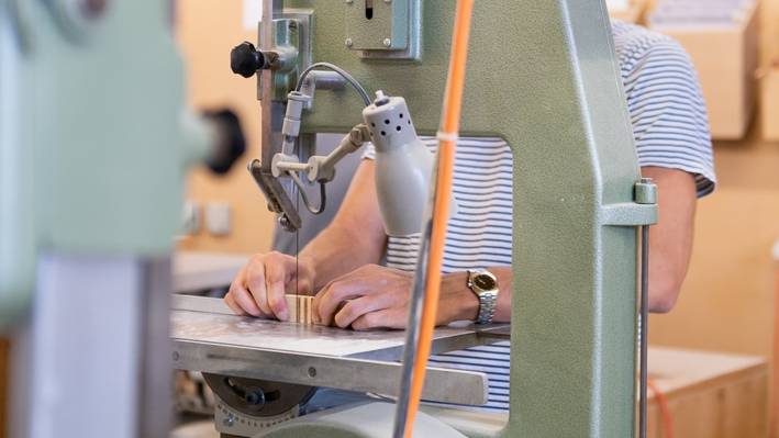 Wer hier studiert, baut seine Modelle selbst. Student bearbeitet ein Werkstück an der Bandsäge in der Modellbauwerkstatt.