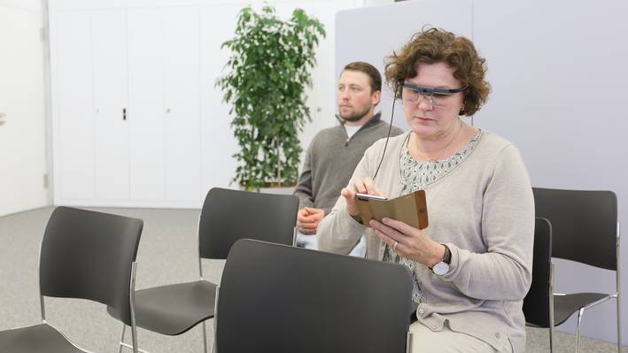 Usability Lab Eine Frau und ein Mann sitzen in einem Raum auf aufgereihten Stühlen