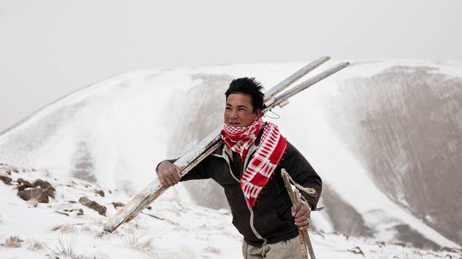 Person carrying a pair of ski in a snowy landscape