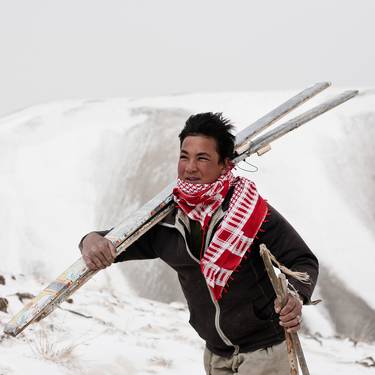 Person carrying a pair of ski in a snowy landscape