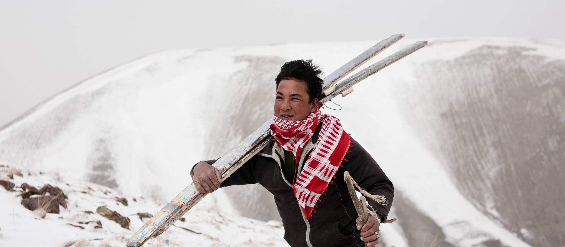 Person carrying a pair of ski in a snowy landscape