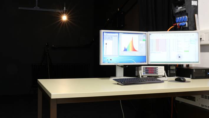 Zwei helle Bildschirme auf einem Schreibtisch in einem dunklen Raum