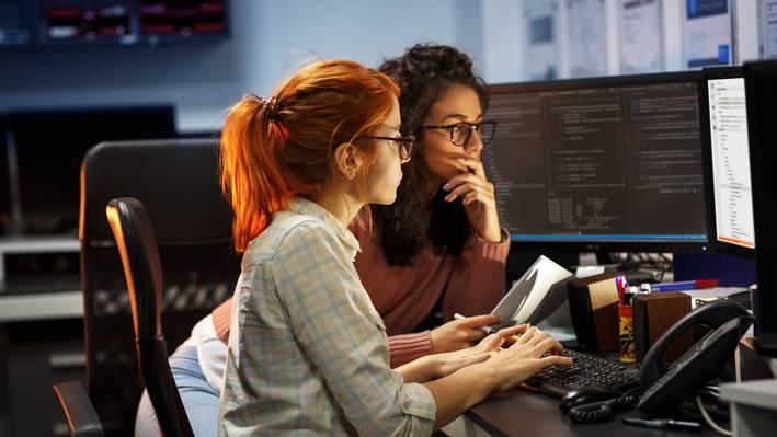 Spannendes Arbeitsumfeld Zwei Absolvierende arbeiten im Büro und wenden KI an.