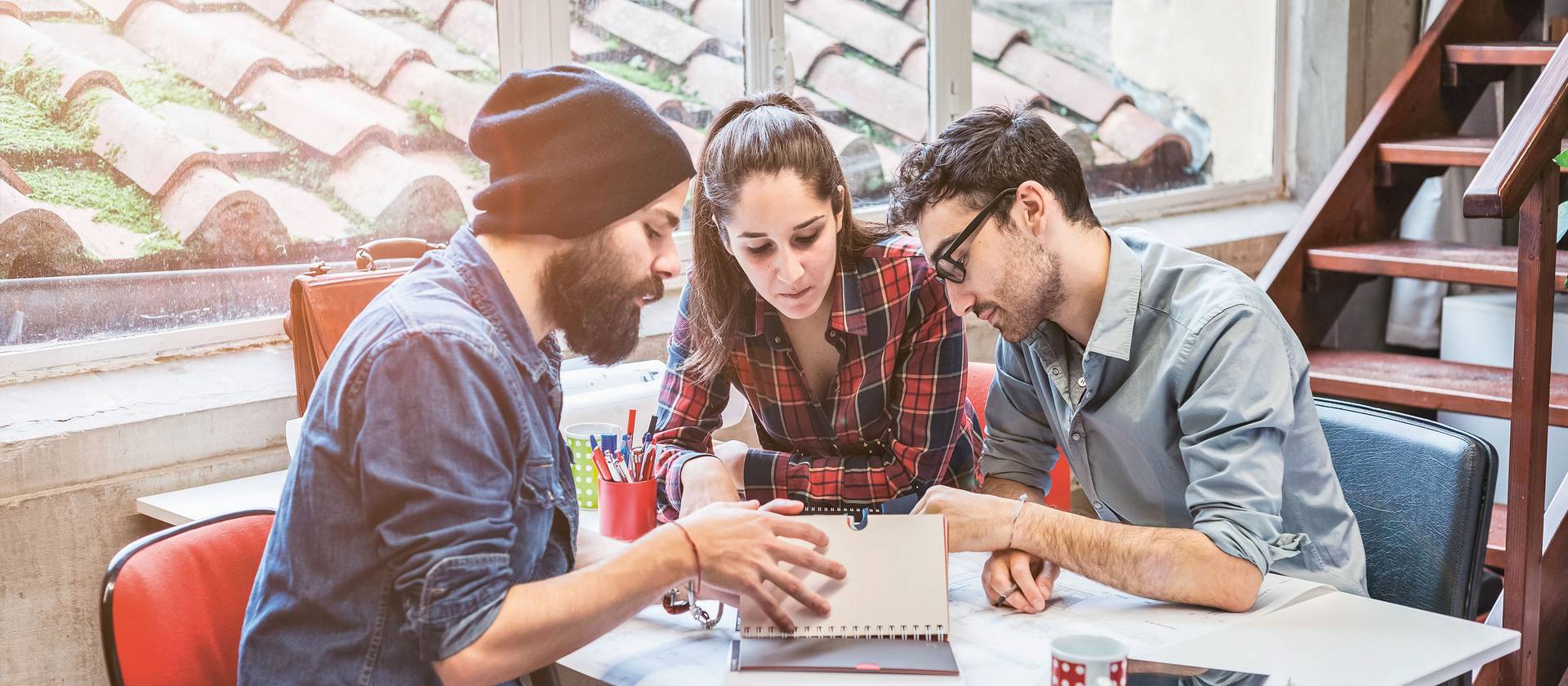 Imagebild Bachelorstudium Tourismus, Studierende sitzen diskutierend an einem Tisch