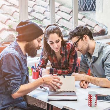 Imagebild Bachelorstudium Tourismus, Studierende sitzen diskutierend an einem Tisch