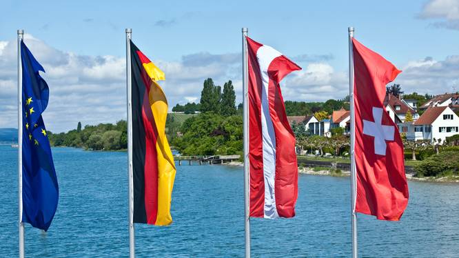 Flags oh European countries flying in front of a blue lake