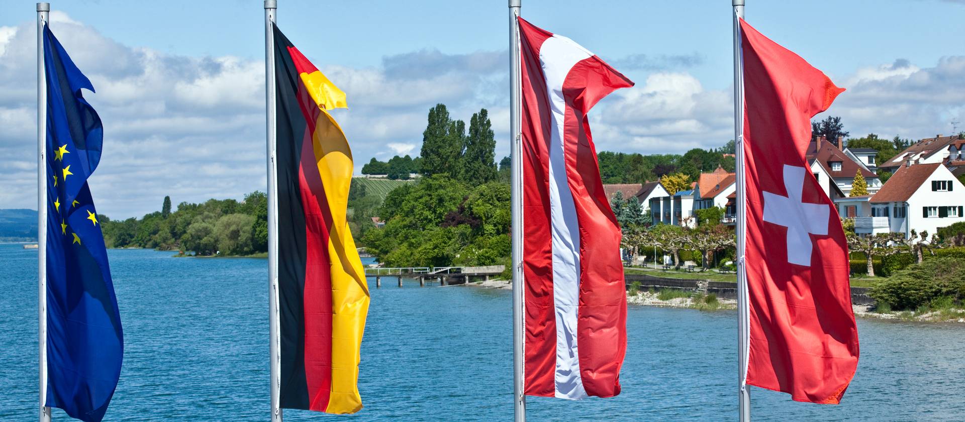 Flags oh European countries flying in front of a blue lake