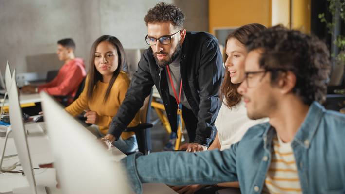 Informatik studieren: Dozent betreut Studierende am Laptop persönlich