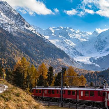 Stunning view of red Rhaetian train running under the Morteratsch Glacier, Grisons, Switzerland