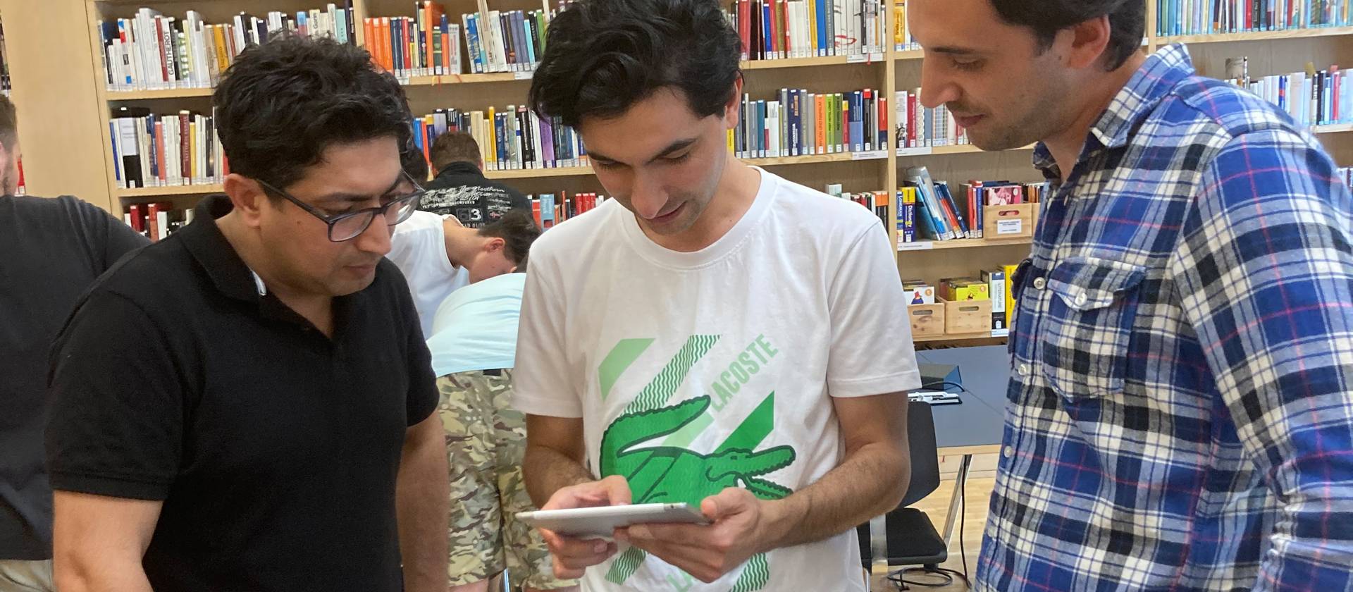 Drei Teilnehmer des Brückenangebots bei der Einführung in die Bibliothek.