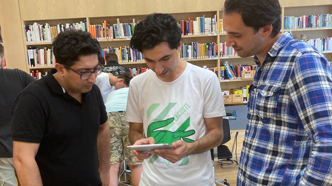 Drei Teilnehmer des Brückenangebots bei der Einführung in die Bibliothek.