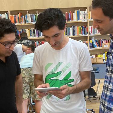 Drei Teilnehmer des Brückenangebots bei der Einführung in die Bibliothek.