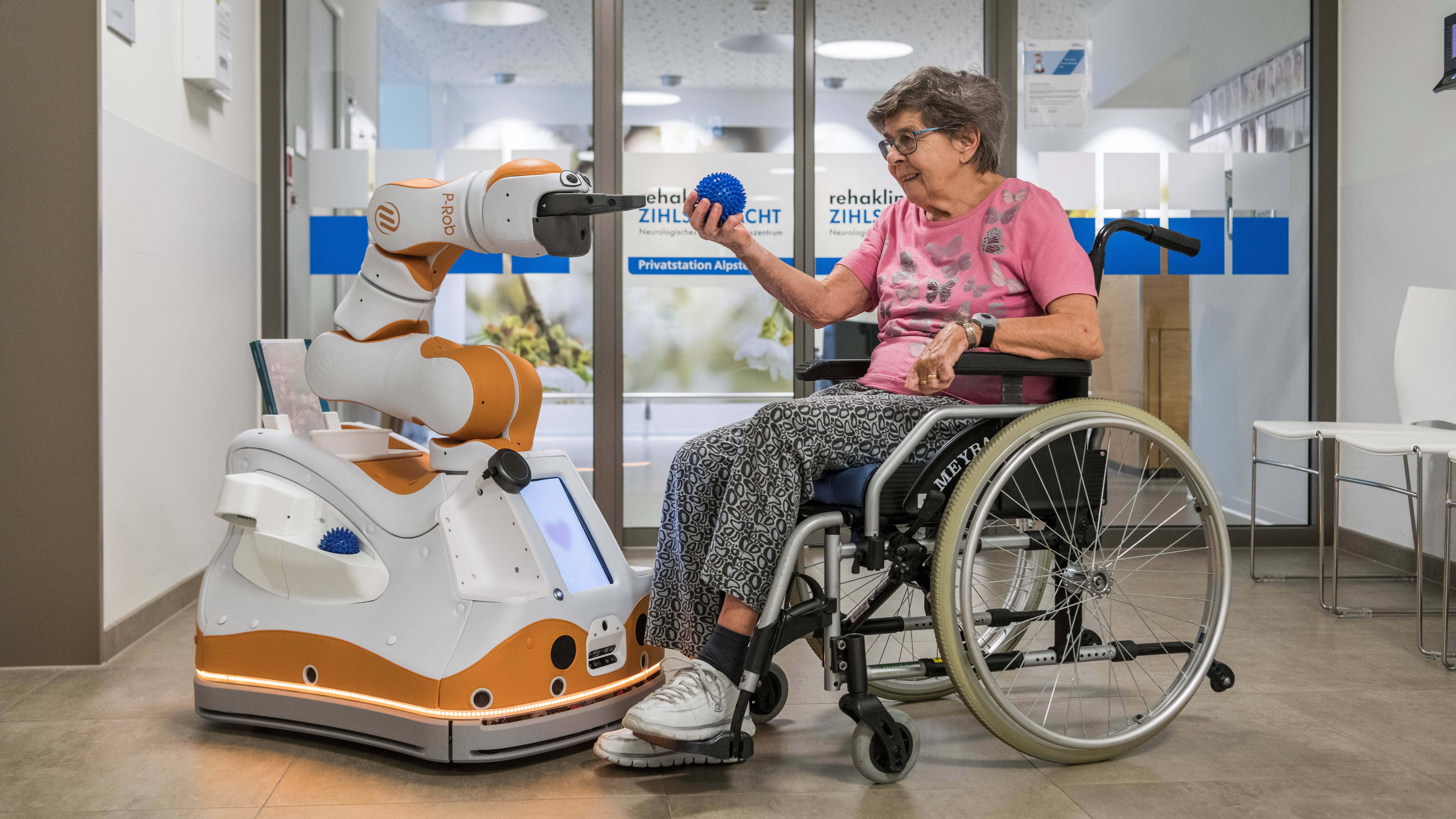 Ein Servicerobotik und eine betagte Frau im Rollstuhl.