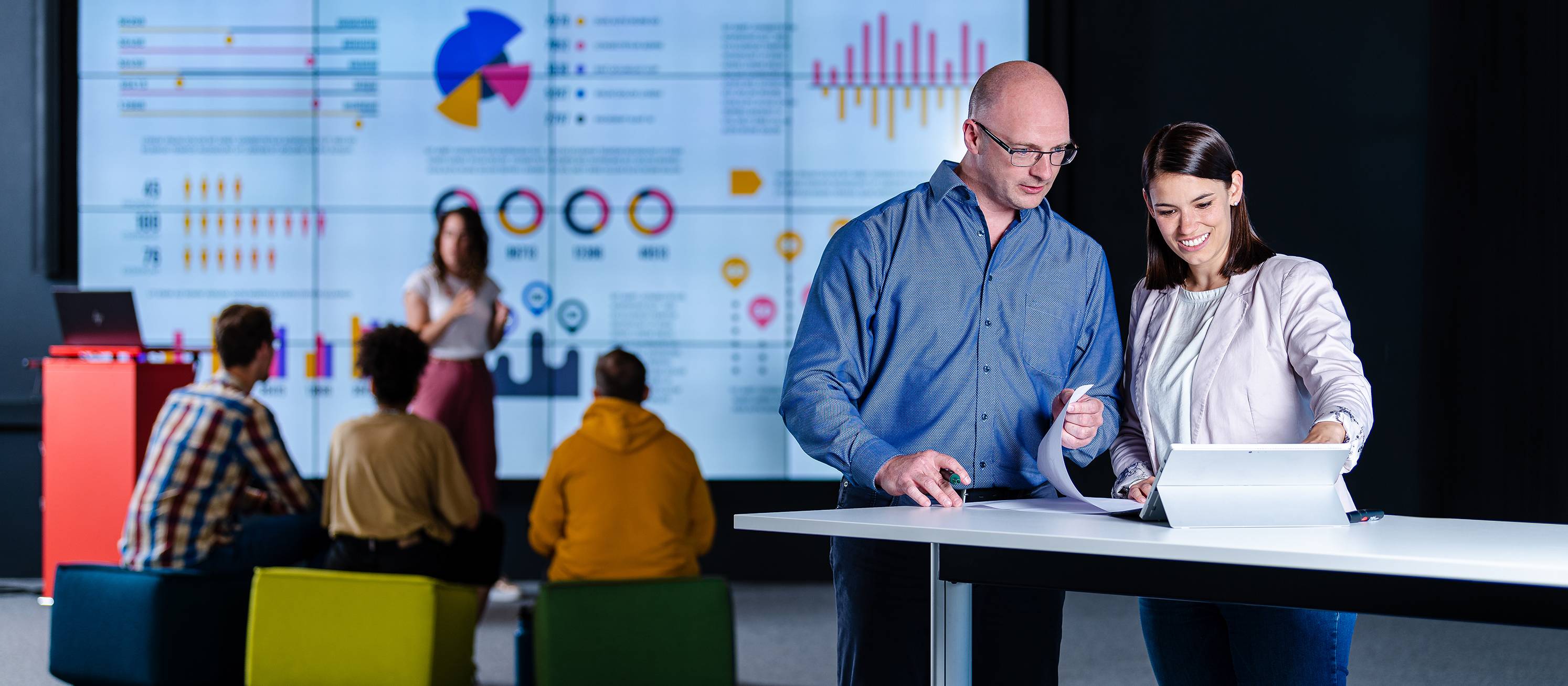 Data Visualization Masterstudierende mit Dashboard im Hintergrund