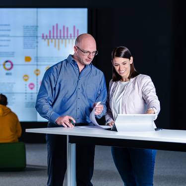 Data Visualization Masterstudierende mit Dashboard im Hintergrund