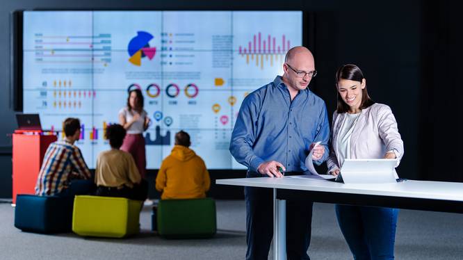 Data Visualization Masterstudierende mit Dashboard im Hintergrund