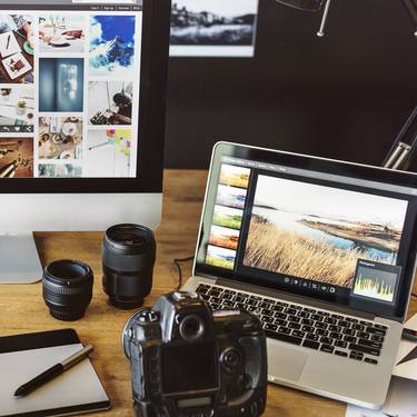 Dektop, Laptop, Kamera, Objektive, Tablet und Fotos auf dem Schreibtisch