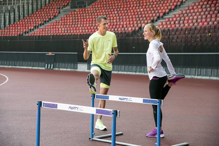 Zwei Studierende machen Dehnübungen im Stadion.