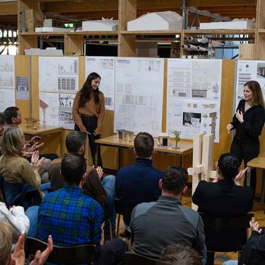 Zwei Architekturstudentinnen der FH Graubünden freuen sich über die Rückmeldungen zu ihrem Entwurf der zukünftigen Bushaltestelle vor dem Fachhochschulzentrum Graubünden. (Bild: FHGR / Barbara Truog)
