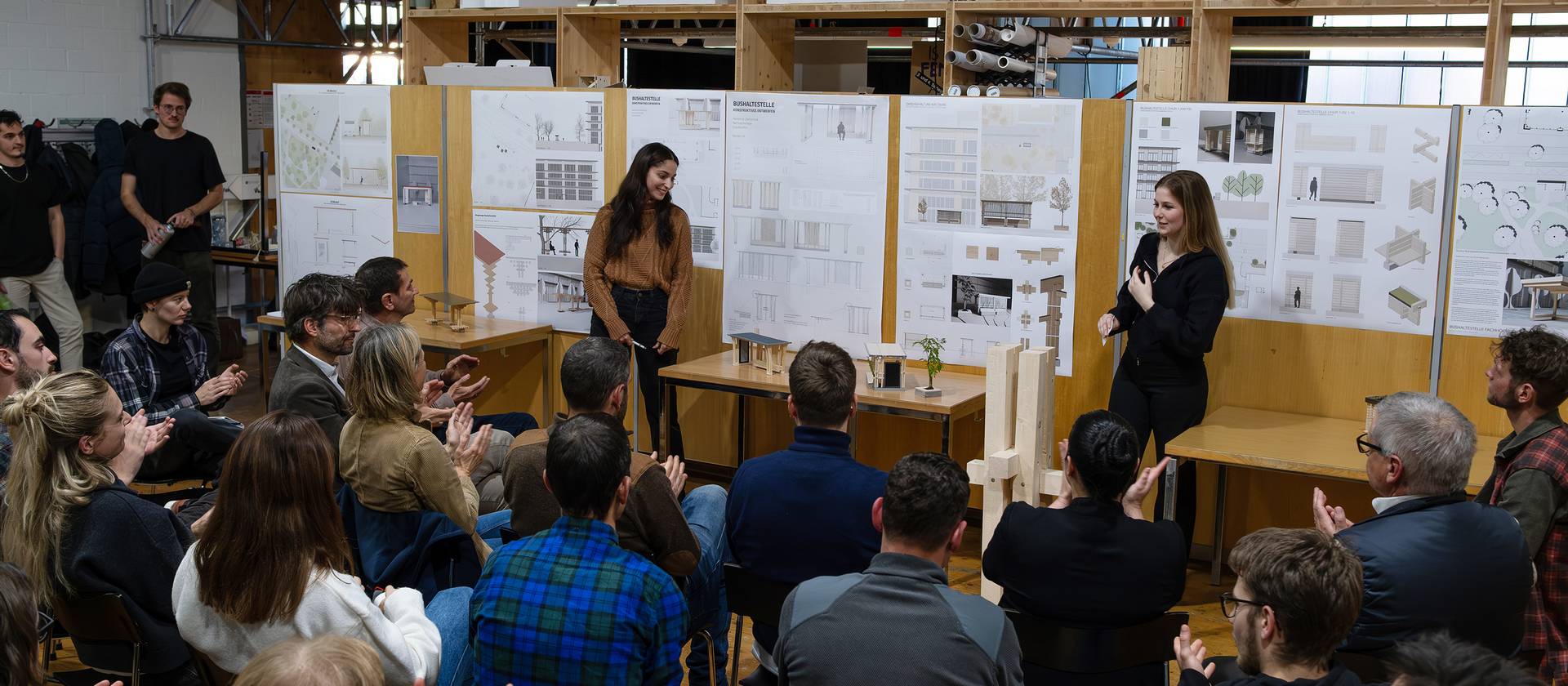 Zwei Architekturstudentinnen der FH Graubünden freuen sich über die Rückmeldungen zu ihrem Entwurf der zukünftigen Bushaltestelle vor dem Fachhochschulzentrum Graubünden. (Bild: FHGR / Barbara Truog)