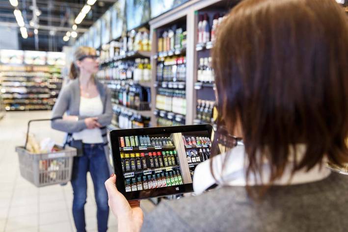 Eine Frau, die eine Tobii Pro Glasses 2 Brille trägt, hält einen Einkaufskorb in einem Supermarkt.