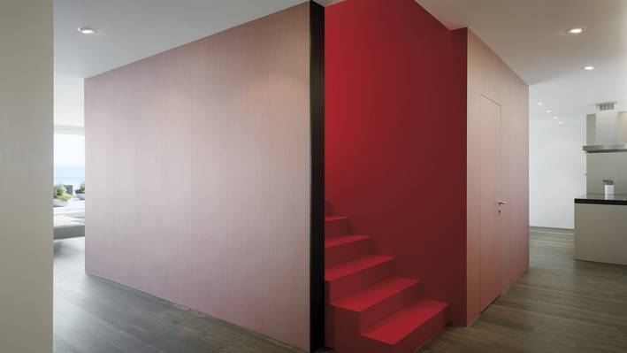 Raumhoher roter Einbau mit Treppe in einem hellen Wohnraum.