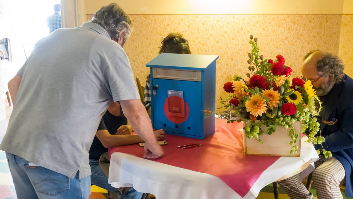 [Translate to Italienisch:] Die Bergeller Bevölkerung schreibt ihre Wünsche und Erwartungen an das Bregaglia Lab auf die "cartolina dei desideri".