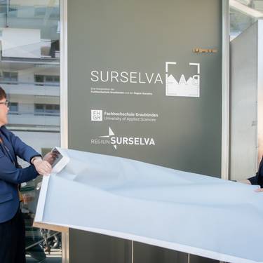 Carmelia Maissen, als Vertreterin der Surselva, und Ulrike Zika, als Vertreterin der FH Graubünden, enthüllen das Logo des Surselva Lab.