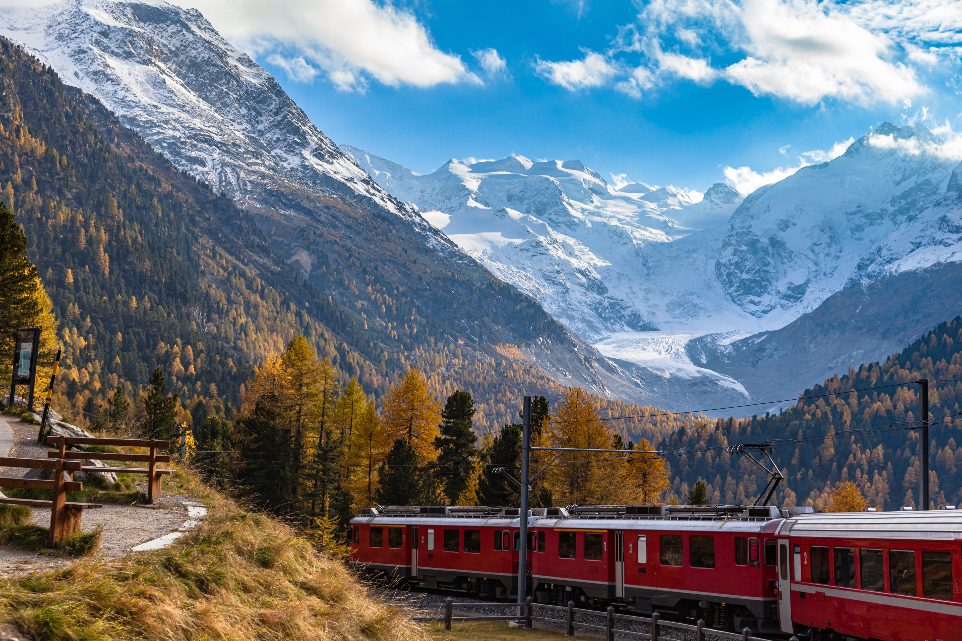 Stunning view of red Rhaetian train running under the Morteratsch Glacier, Grisons, Switzerland
